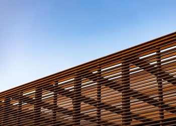 Wooden slat shading structure with roof against blue sky
